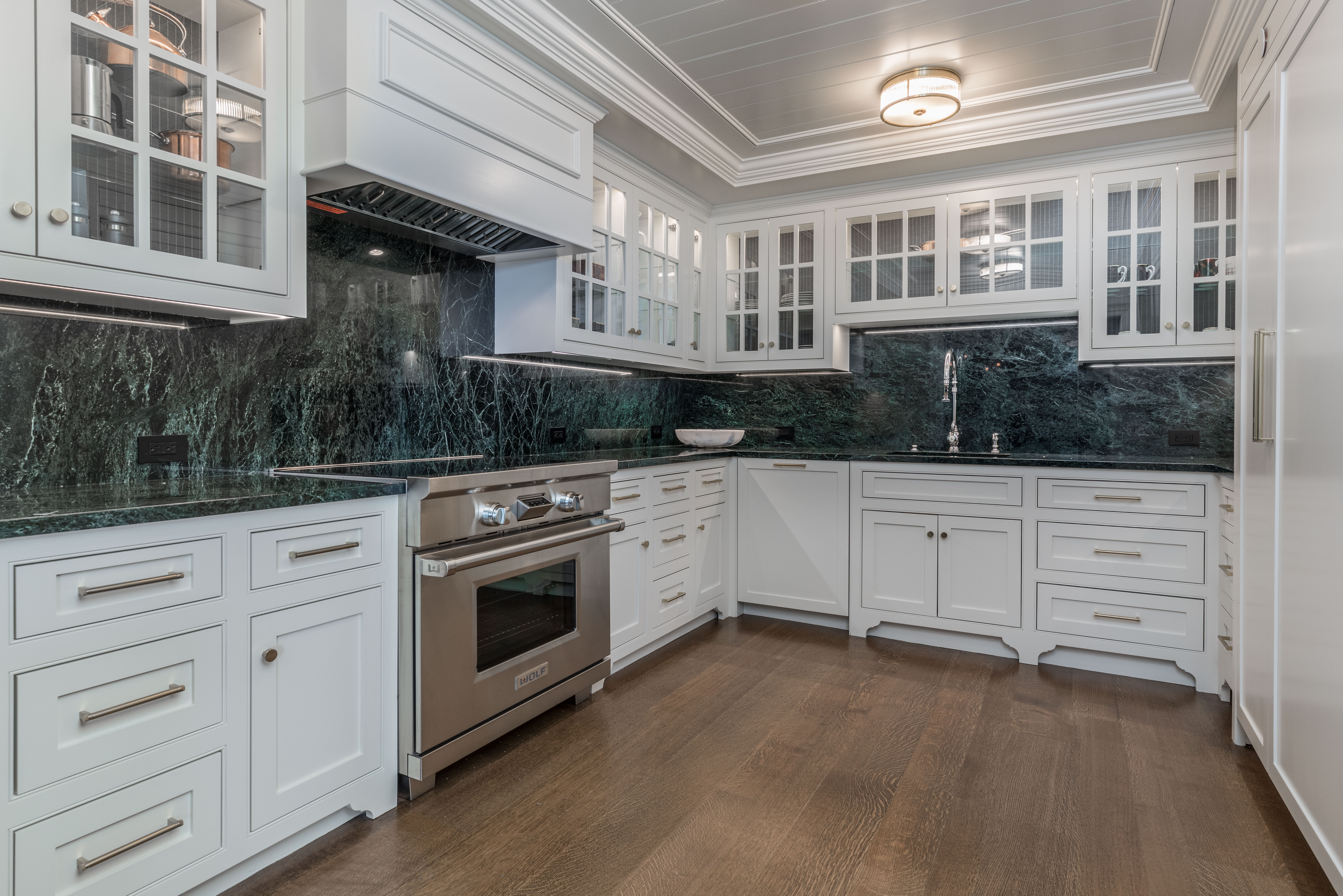 Kitchen with green marble and white cabinetry